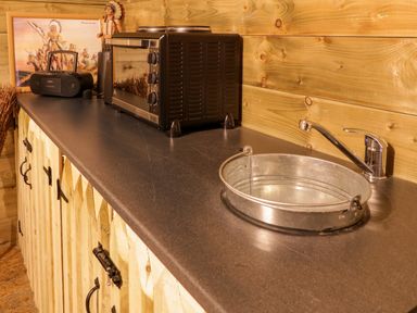 A countertop with a metal bucket sink a toaster oven a small radio and wooden cabinets in a kitchen at Apache Falls Lodge in Castlerock