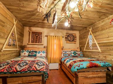 A bedroom with two beds with patterned bedding wooden walls and ceiling at Apache Falls Lodge in Castlerock