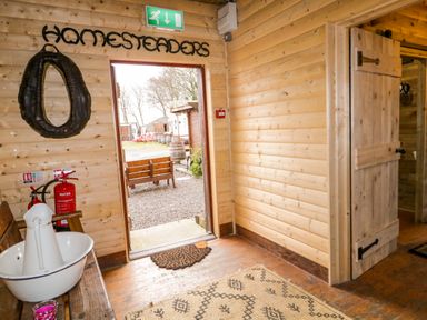 A wooden entryway with a bench a white basin and pitcher fire extinguishers and an open door showing an outdoor area at Apache Falls Lodge in Castlerock