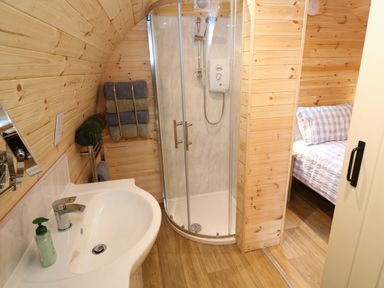 A bathroom with a shower, sink, towels, and a view into a bedroom with a bed at Audrey in Penzance near Newlyn