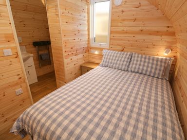 A bedroom with a bed with checkered bedding and a small window at Lloyd in Penzance near Newlyn