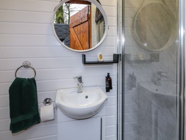 A bathroom with a sink mirror towel toilet paper holder and a shower at Hexagon Hut - Dec Update in Dungiven Londonderry