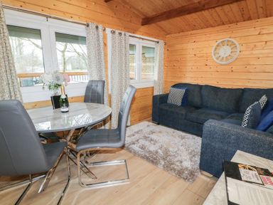 A wooden interior room with a round table and four chairs next to a blue sofa and a fluffy rug at Mill View in Dungiven Londonderry