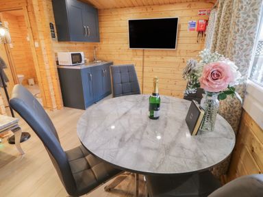 A dining area with a round marble table and black chairs next to a kitchenette with microwave and sink at Mill View in Dungiven Londonderry