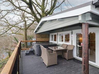 An outdoor porch with a table and four chairs and a covered hot tub surrounded by trees at Mill View in Dungiven Londonderry