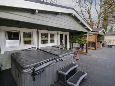 An outdoor deck with a hot tub and steps a round table with chairs and a covered seating area at The Castle in Dungiven Londonderry