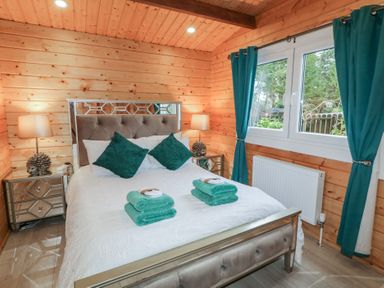 A bedroom with a double bed two teal pillows teal towels on bed wooden walls and teal curtains at The Castle in Dungiven Londonderry