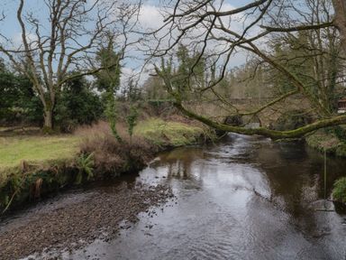 A river with bare trees and a stone bridge in the background at Hazel in Dungiven Londonderry