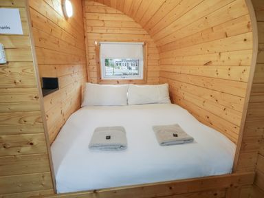 A small bedroom with wooden walls a bed two pillows two folded towels and a window at Juniper in Dungiven Londonderry