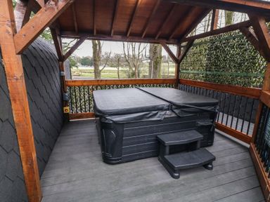 A covered outdoor area with a hot tub and steps surrounded by wooden beams at Birch in Dungiven Londonderry