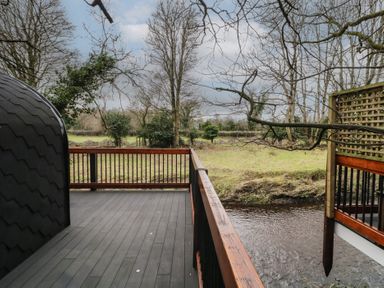 A wooden deck with railings overlooking a river and leafless trees at Yew in Dungiven Londonderry