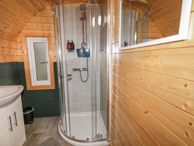 A bathroom with a corner shower enclosure a sink cabinet a small window and wooden panel walls at Elm in Dungiven Londonderry