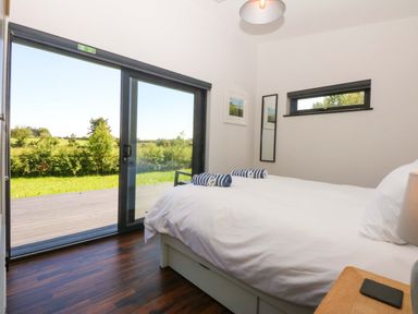 A bedroom with a bed and sliding door at Y Cwt in Moelfre