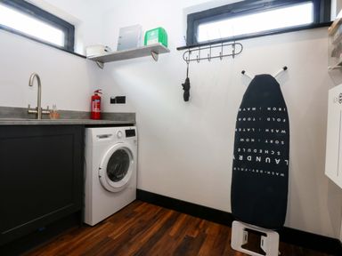 A laundry room with a washing machine and an ironing board at Y Cwt in Moelfre