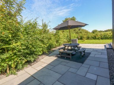 A garden with a table and bench under an umbrella at Y Cwt Moelfre