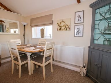 A dining area with a wooden table and four chairs a window with a beige blind and a gray cabinet with glassware at Hillview in Stottesdon near Cleobury Mortimer