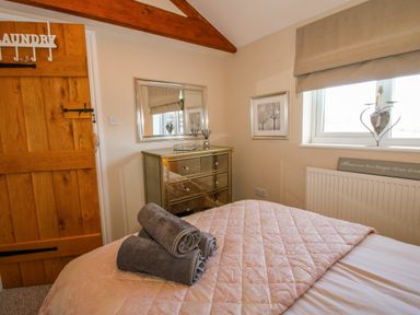 A bedroom with a wooden door mirror chest of drawers and rolled towels on the bed at Hillview in Stottesdon near Cleobury Mortimer