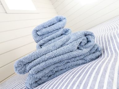 Blue towels folded on striped fabric surface in a room with white paneled walls and skylight at Teg in Prospidnick near Porthleven