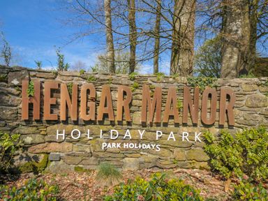 A sign for Hengar Manor Holiday Park surrounded by greenery near St Tudy