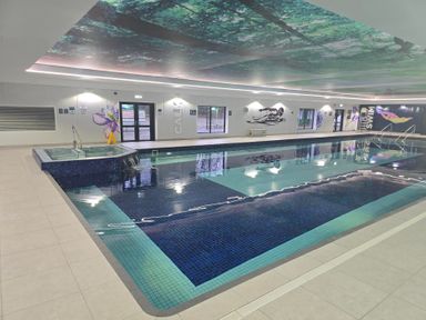 An indoor swimming pool with steps and windows at Cornish Woodland Retreat near St Tudy
