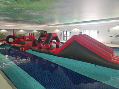 An inflatable obstacle course in an indoor pool at Cornish Woodland Retreat Near St Tudy