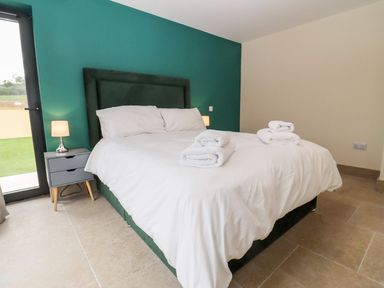 A bedroom with a double bed white bedding bedside table lamp and towels on the bed at Bears Court Barn 3 Little Rissington near Bourton-On-The-Water