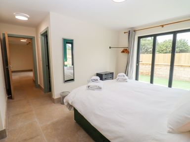 A bedroom with a bed with towels a small drawer and a window with curtains at Bears Court Barn 3 Little Rissington near Bourton-On-The-Water