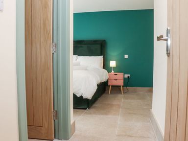 A bedroom with a bed white bedding and a bedside table with a lamp at Bears Court Barn 3 in Little Rissington near Bourton-On-The-Water