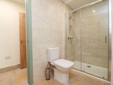 A bathroom with a toilet and a glass-enclosed shower at Bears Court Barn 3 Little Rissington near Bourton-On-The-Water