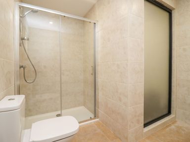 A bathroom with a toilet shower with glass door and frosted window at Bears Court Barn 3 in Little Rissington near Bourton-On-The-Water