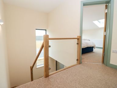 A hallway with stairs and an open door leading to a bedroom at Bears Court Barn 3 in Little Rissington near Bourton-On-The-Water