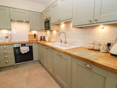 A kitchen with cabinets, a sink, oven, microwave, toaster, kettle, and canisters at Bears Court Barn 4 Little Rissington near Bourton-On-The-Water