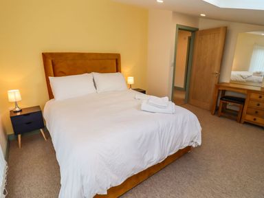 A bedroom with a double bed bedside tables with lamps and a dressing table with stool at Bears Court Barn 4 Little Rissington near Bourton-On-The-Water