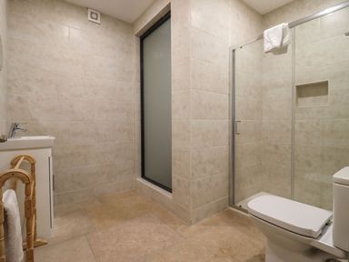 A bathroom with a toilet sink glass shower enclosure and towel rack at Bears Court Barn 4 in Little Rissington near Bourton-On-The-Water