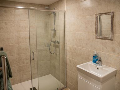 A bathroom with a glass shower enclosure a small white sink with a faucet and a mirror above it at Bears Court Barn 7 Little Rissington near Bourton-On-The-Water