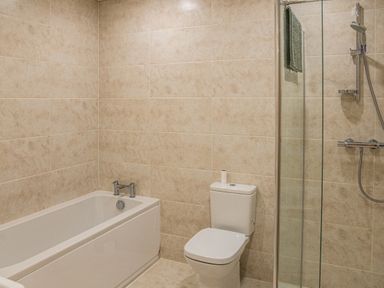 A bathroom with a bathtub toilet and a glass-enclosed shower at Bears Court Barn 7 Little Rissington near Bourton-On-The-Water