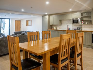 A kitchen and dining area with wooden dining table and chairs and grey cabinets at Bears Court Barn 8 Little Rissington near Bourton-On-The-Water