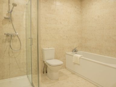 A bathroom with a glass-enclosed shower a toilet and a bathtub with a towel at Bears Court Barn 5 Little Rissington near Bourton-On-The-Water