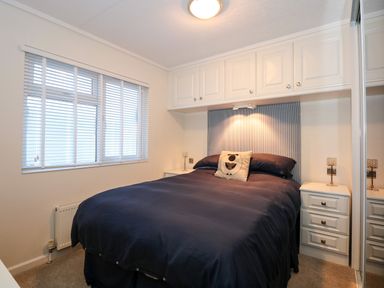 A bedroom with a bed and overhead storage cabinets at Un Diwrnod One Day The Warren T22 The Warren near Abersoch