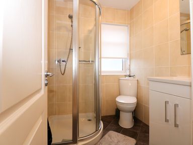 A bathroom with a shower enclosure a toilet and a sink cabinet at Un Diwrnod One Day The Warren T22 The Warren near Abersoch