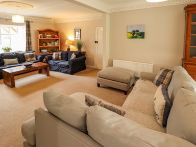 A living room with sofas a wooden coffee table a bookshelf and a cabinet at Natterjacks in Syderstone