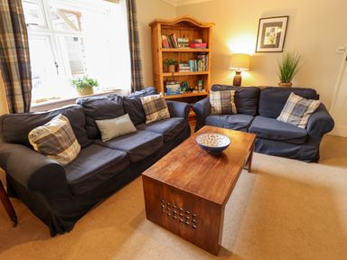 A sitting room with two blue sofas a wooden coffee table and a wooden bookshelf at Natterjacks in Syderstone