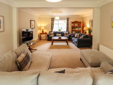 A living room with sofas a coffee table a television and a bookshelf at Natterjacks in Syderstone