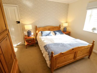 A bedroom with a wooden bed and two bedside tables with lamps at Natterjacks in Syderstone