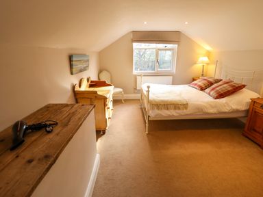 A bedroom with a bed pillows bedside tables a chest of drawers chair and a window at Natterjacks in Syderstone