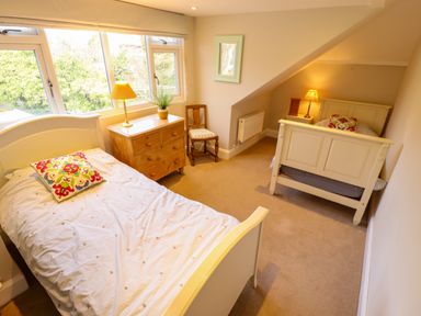 A bedroom with two single beds a wooden chest of drawers a chair and table lamps at Natterjacks in Syderstone