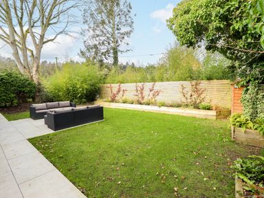A garden with grass lawn a wooden fence outdoor sofa set and plants at Natterjacks in Syderstone