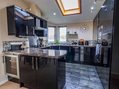 A kitchen with black cabinets granite countertops and skylight at Otters Reach near Carnforth