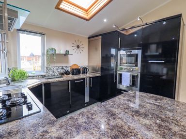 A kitchen with black cabinets a countertop stove oven and microwave at Otters Reach near Carnforth