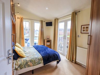 A bedroom with a bed near windows and glass doors at Otters Reach near Carnforth